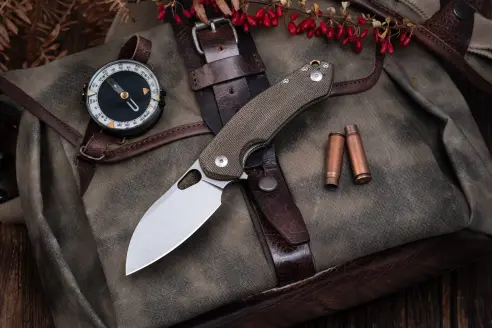 Knife on top of bag with a compass and empty shell casings laying there