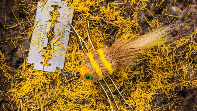 deer-hair fly sits next to razor on bed of shavings