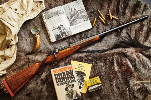 Rifle on fur with cartridges, Ruark book