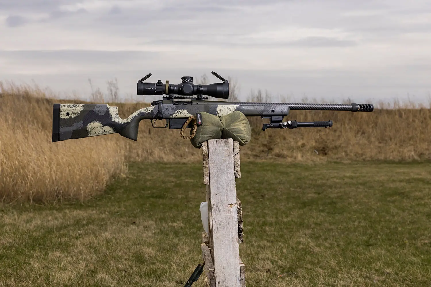 Rifle propped on shooting bag on fence