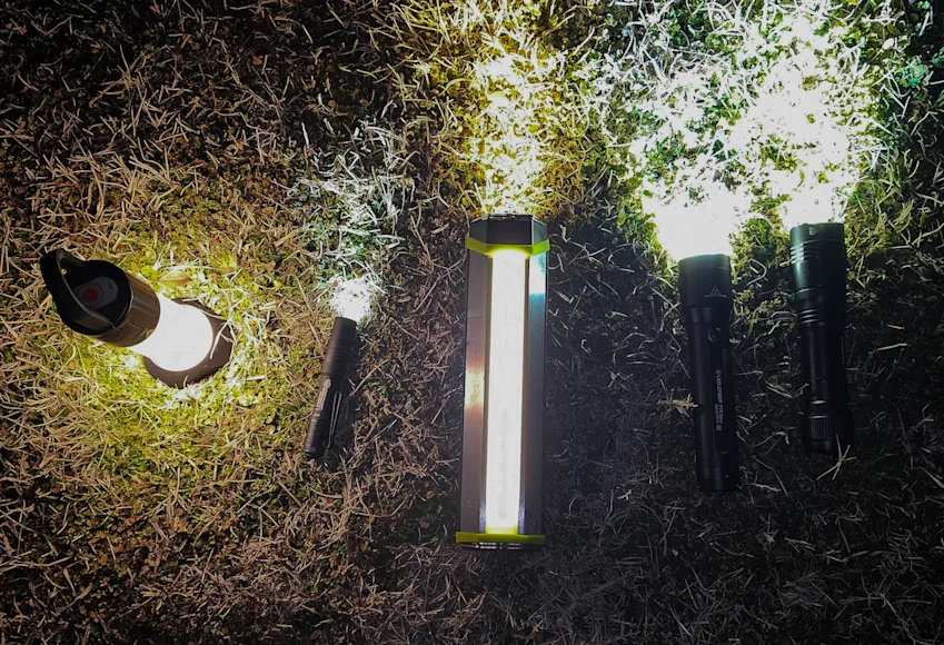 Best camping flashlights lined up on grass at night