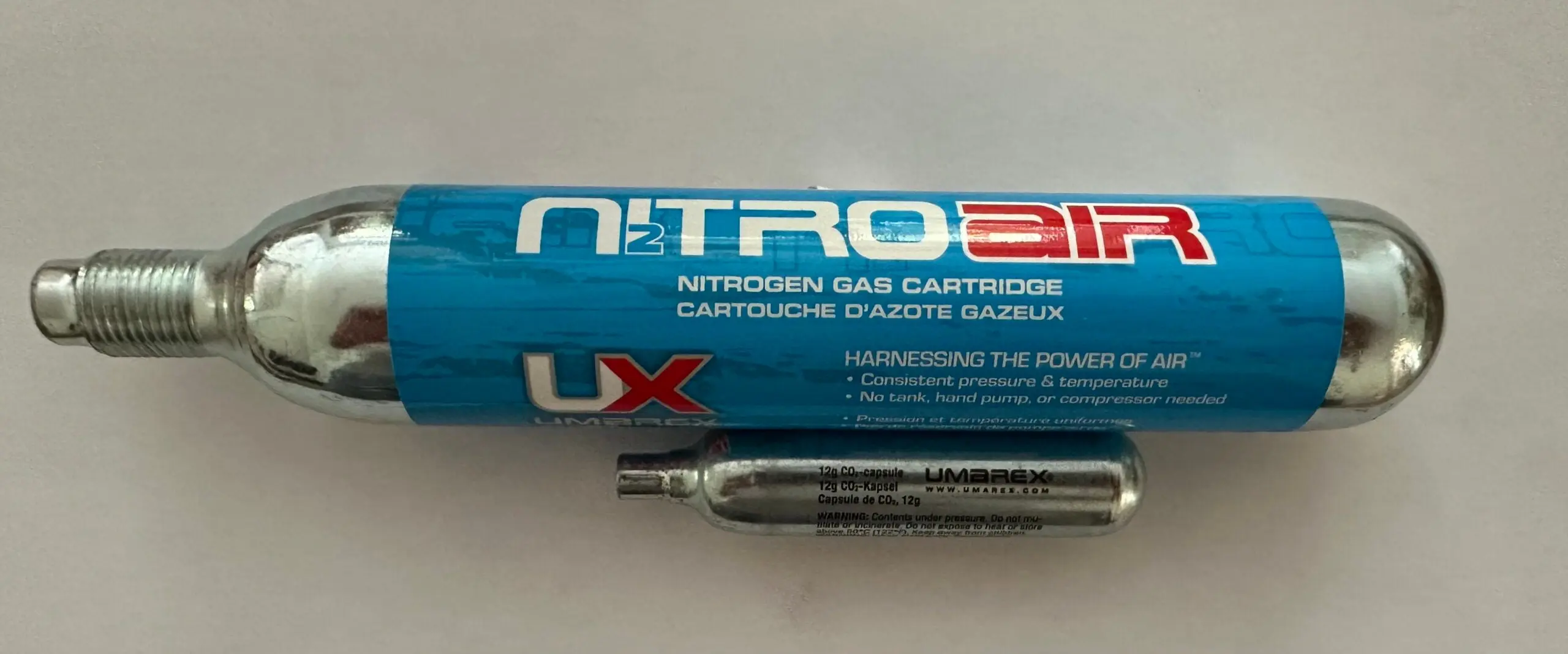 A nitrogen cartridge next to a typical CO2 capsule.