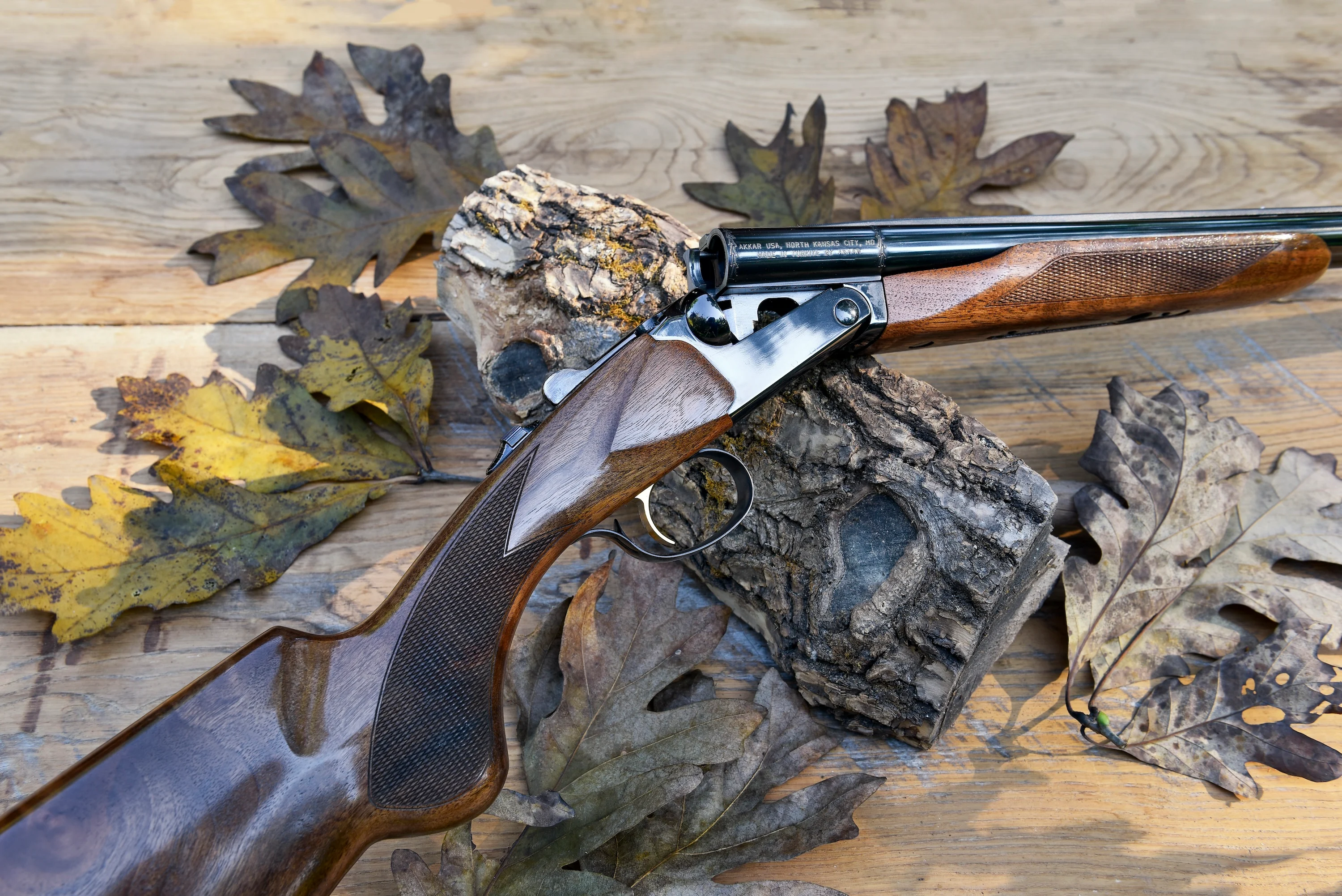 The new Akkar High Noon side-by-side shotgun on barn boards with oak leaves.
