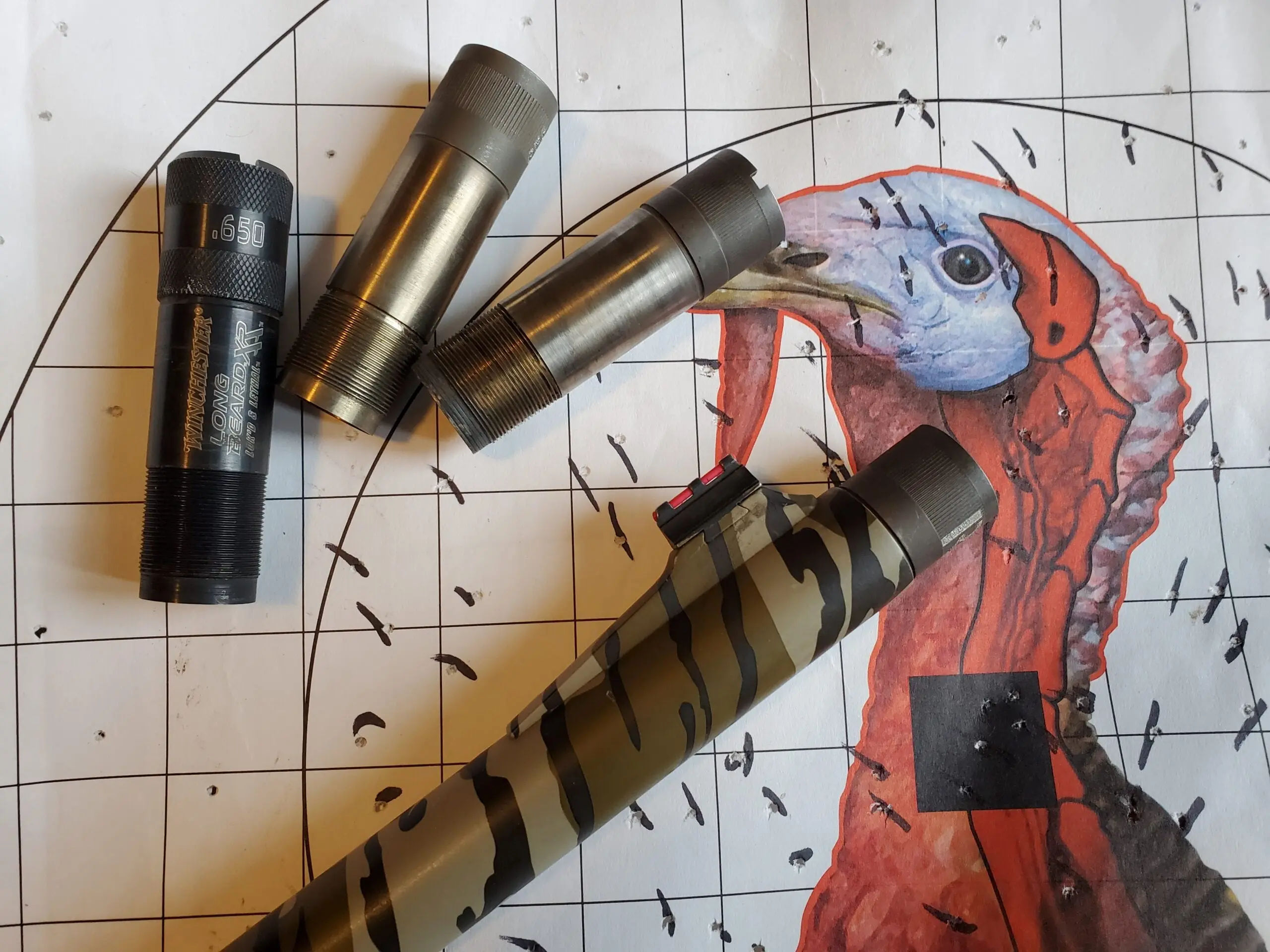 Three shotgun chokes next to a turkey target.