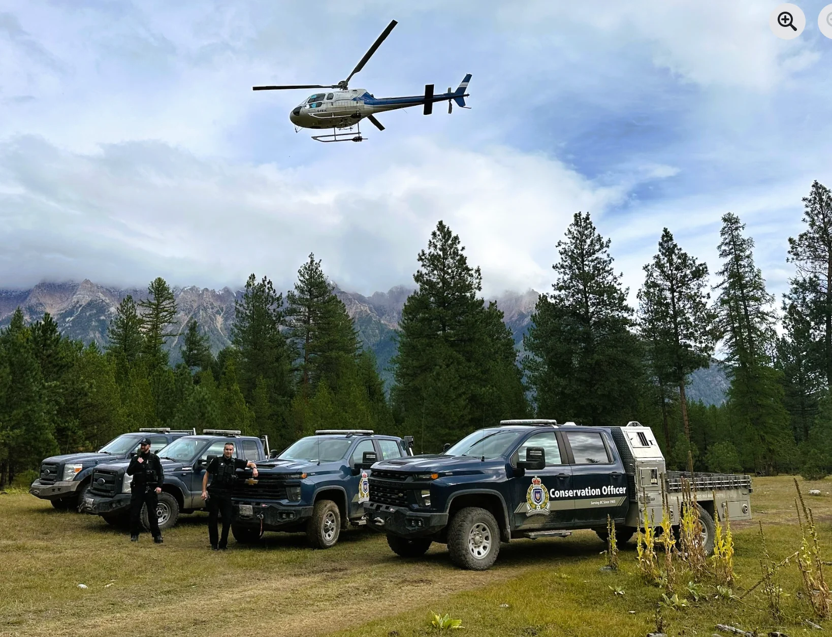 A Canadian rescue helicopter hovers above a fleet of search-and-rescue vehicles.
