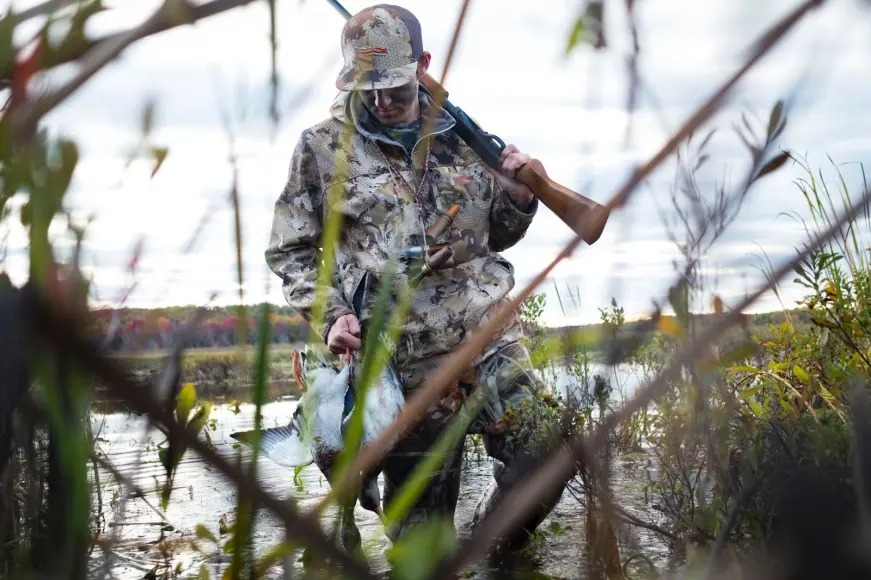 Hunter wearing Sitka duck hunting jacket, pants, and hat in the marsh