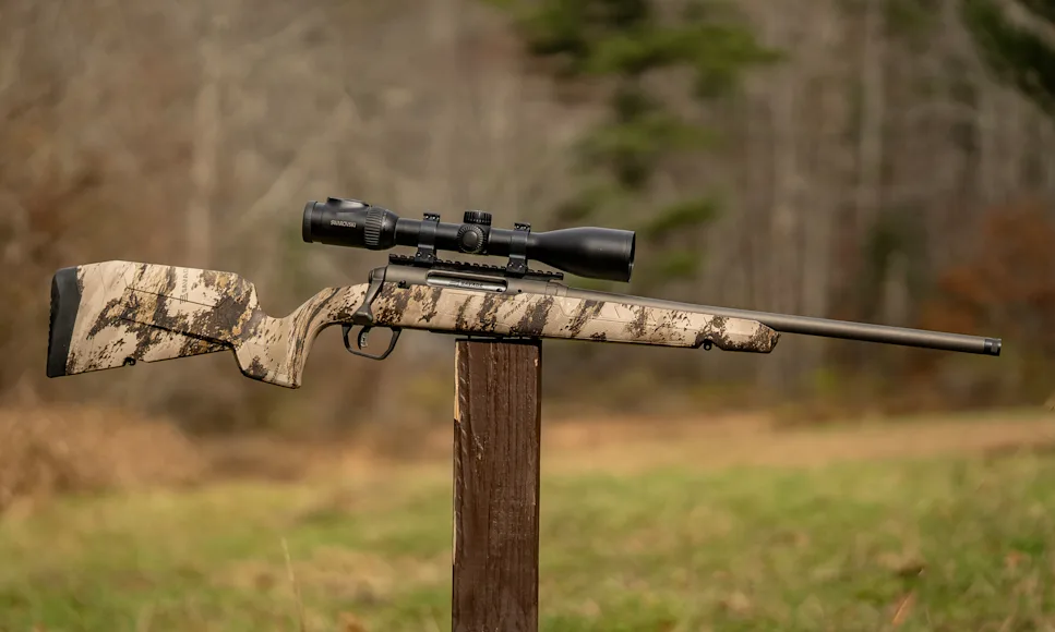 The new Savage Axis 2 Pro bolt-action rifle balance on a post with woods in background.