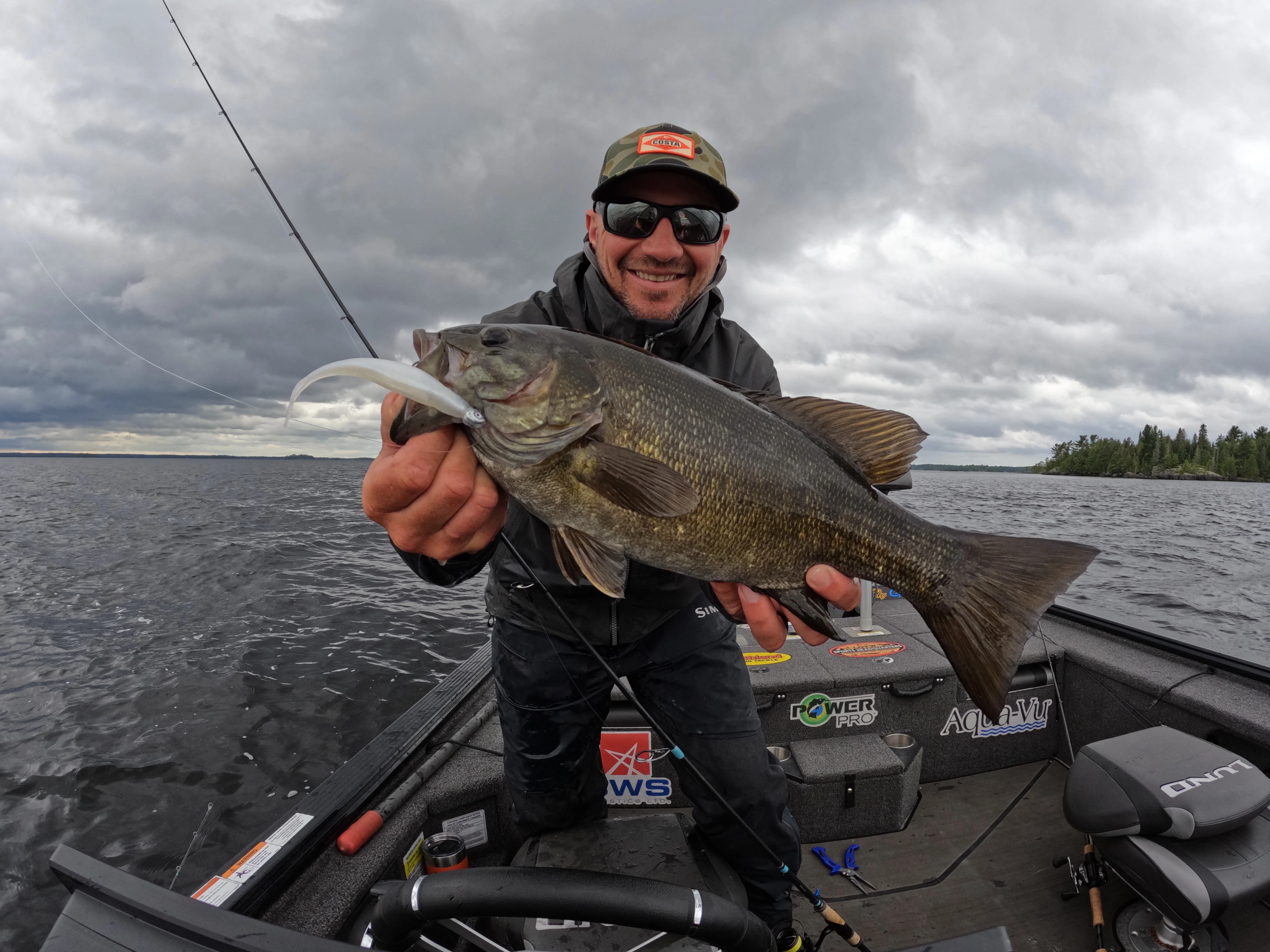 Angler holding up smallmouth bass on bass boat