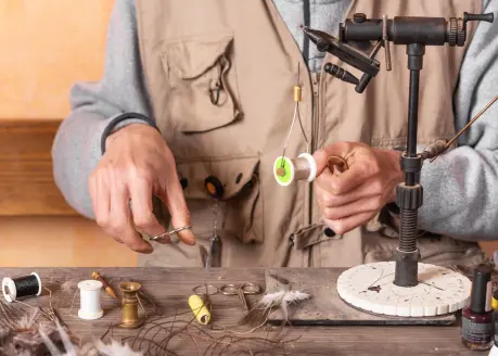 A man ties flies at tying bench. 