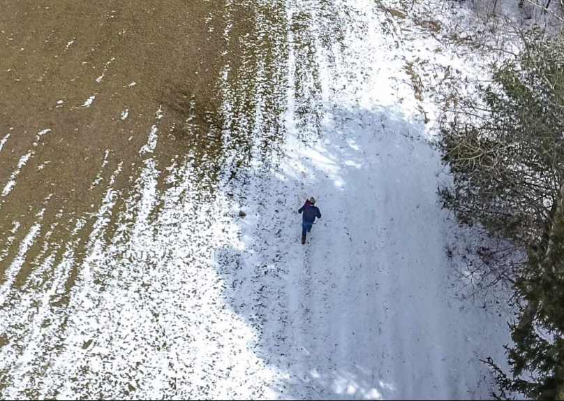 Overhead view of someone frost-seeding a field in March.