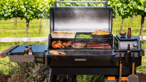 Trager pellet grill and smoker open with meat and vegetables grilling