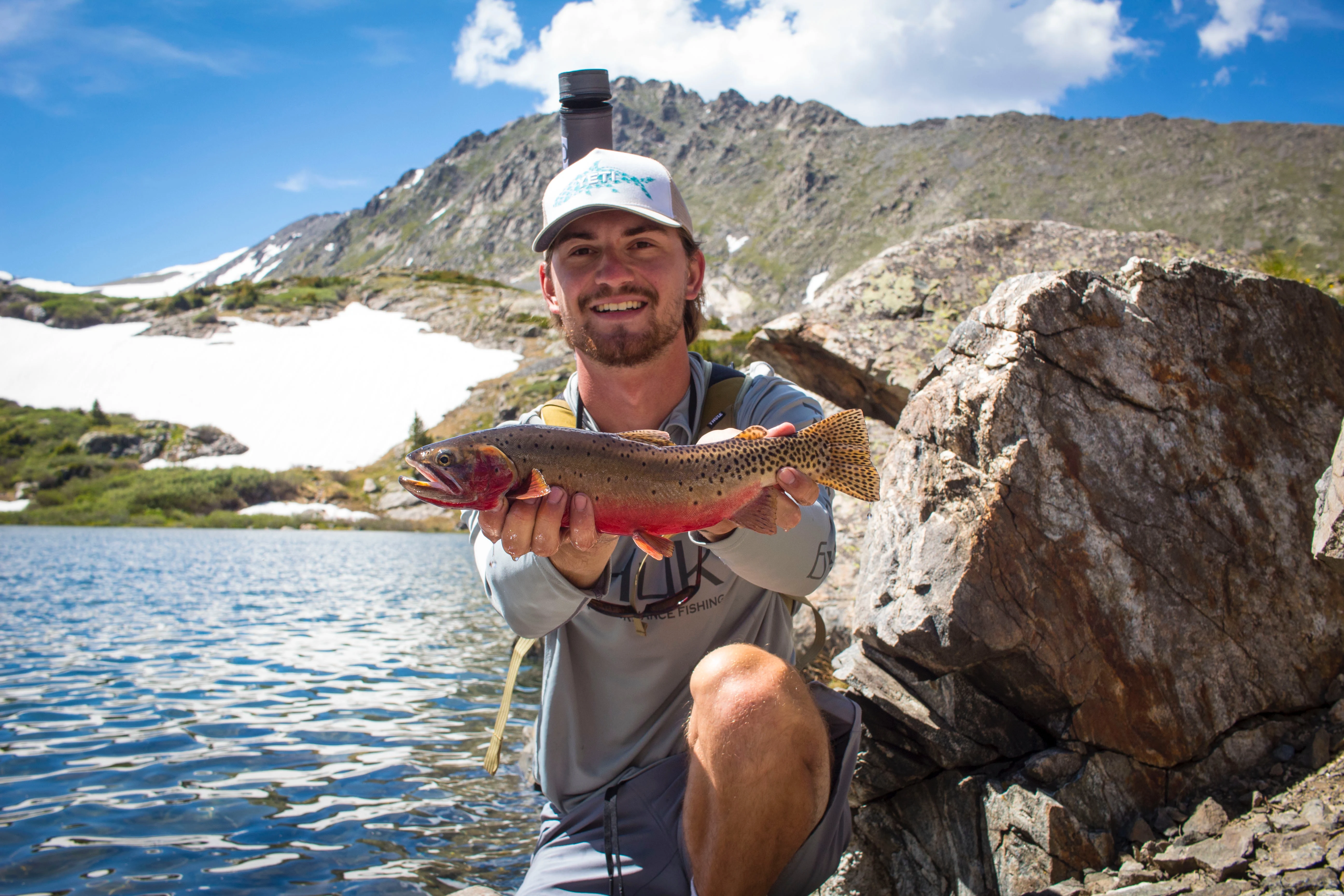 Angler holding up cutthroat trout with mountains in the background