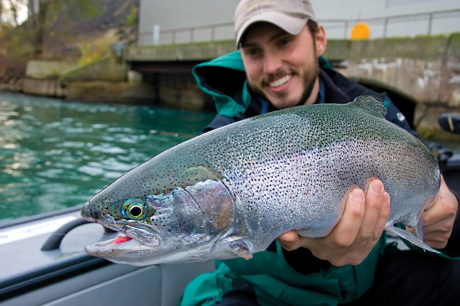 smiling angler on boat holds up steelhead