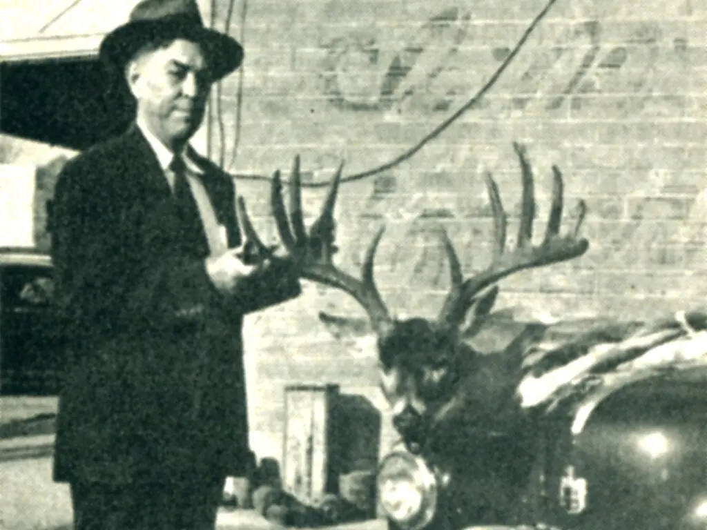 Black and white image of a man and a deer's head.