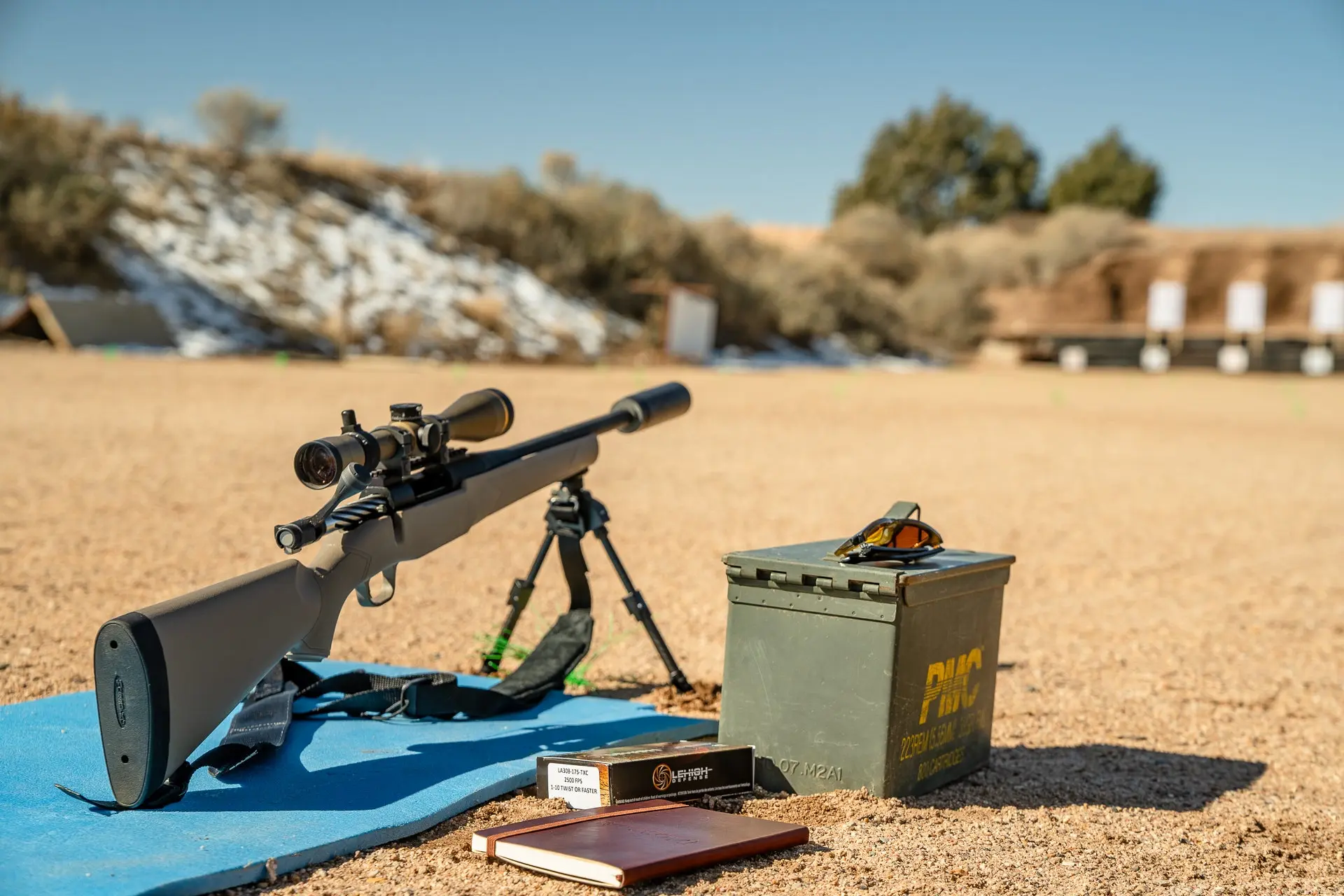 A Mossberg Patriot bolt-action rifle is set up on a shooting pad at a rifle range.