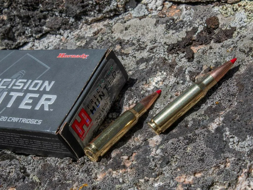 A box of Hornady Precision Hunter and ammunition on a rock.