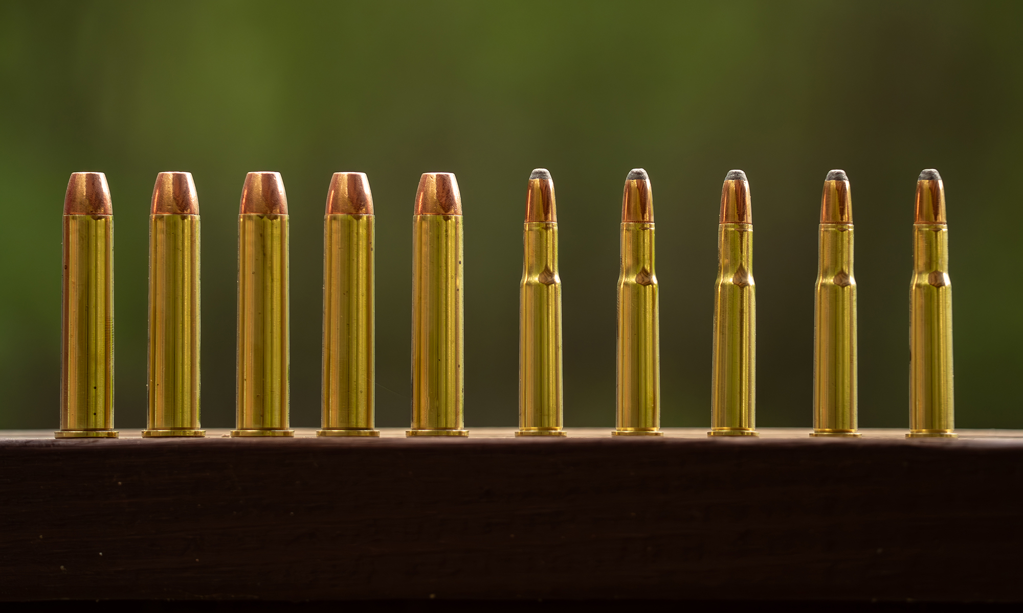 A row of 45-70 vs 30-30 cartridges, lined up on a railing.