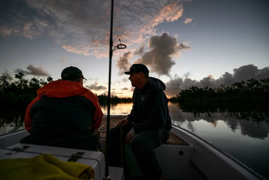 Two anglers on a boat at sunset.