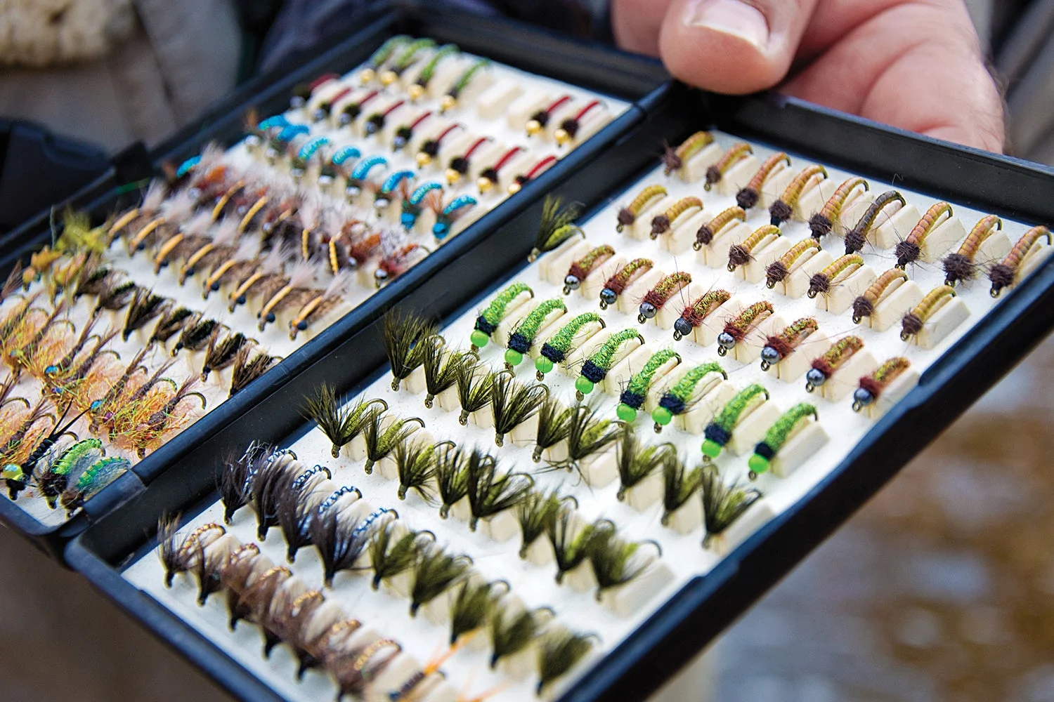 Open fly box shows many flies organized by size and type.