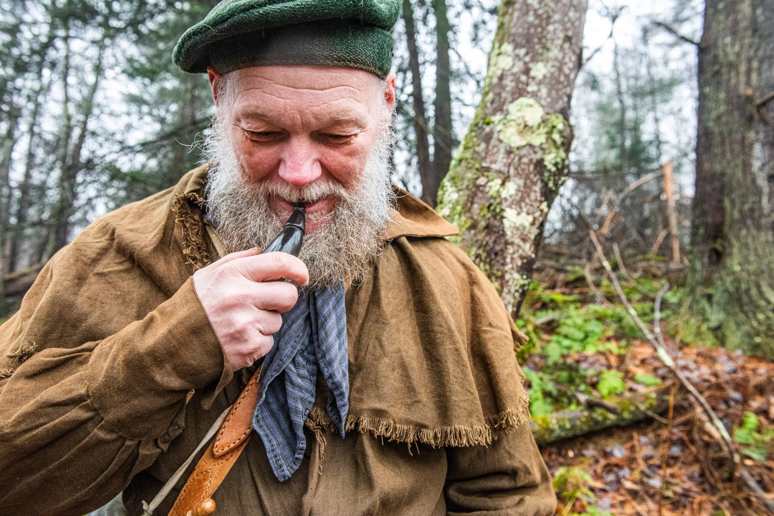 Traditional flintlock hunter uses he teeth to remove the cap of a powder horn