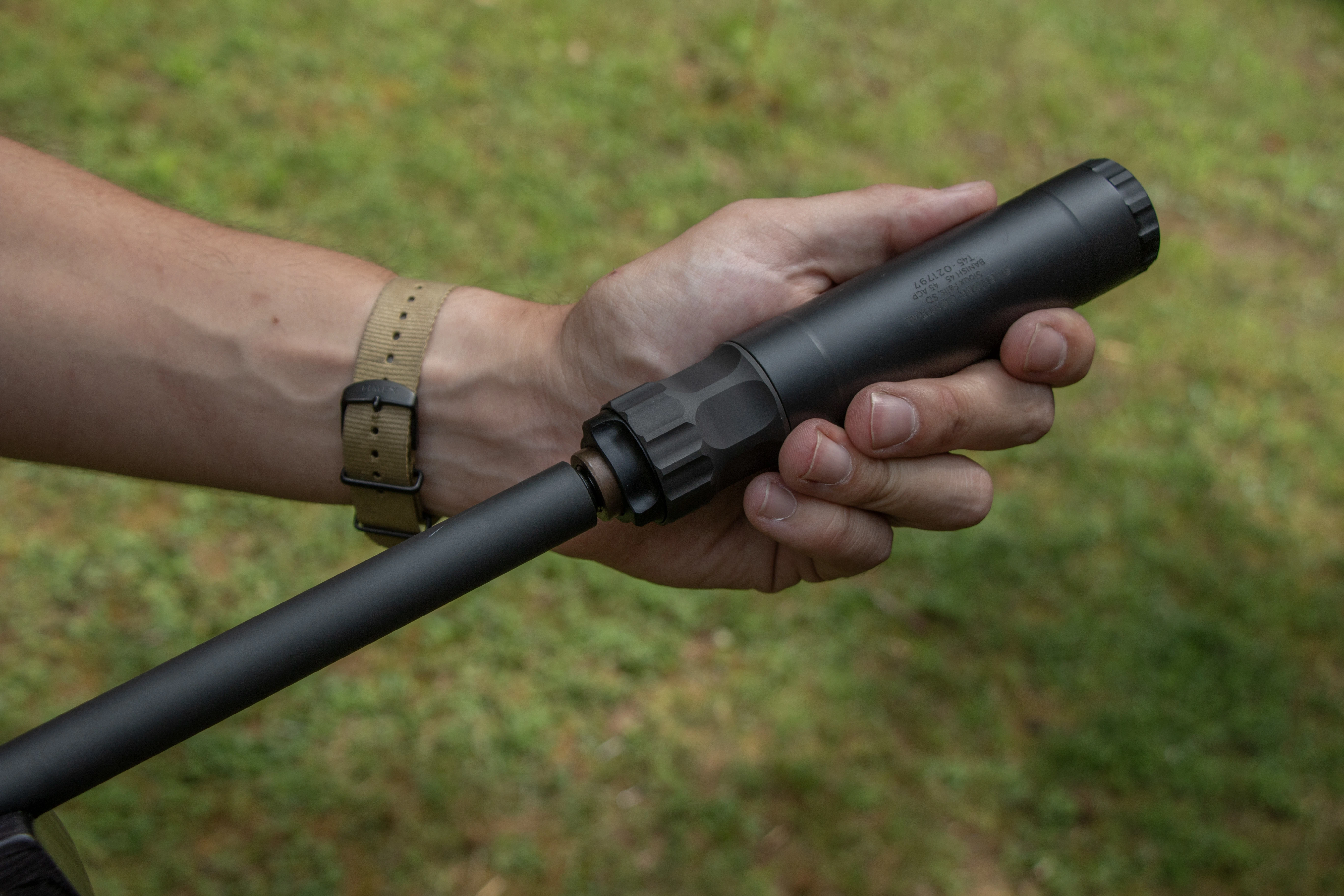 A shooter screws a suppressor to the end of the Hammerli Arms Force B1 rifle's threaded barrel. 