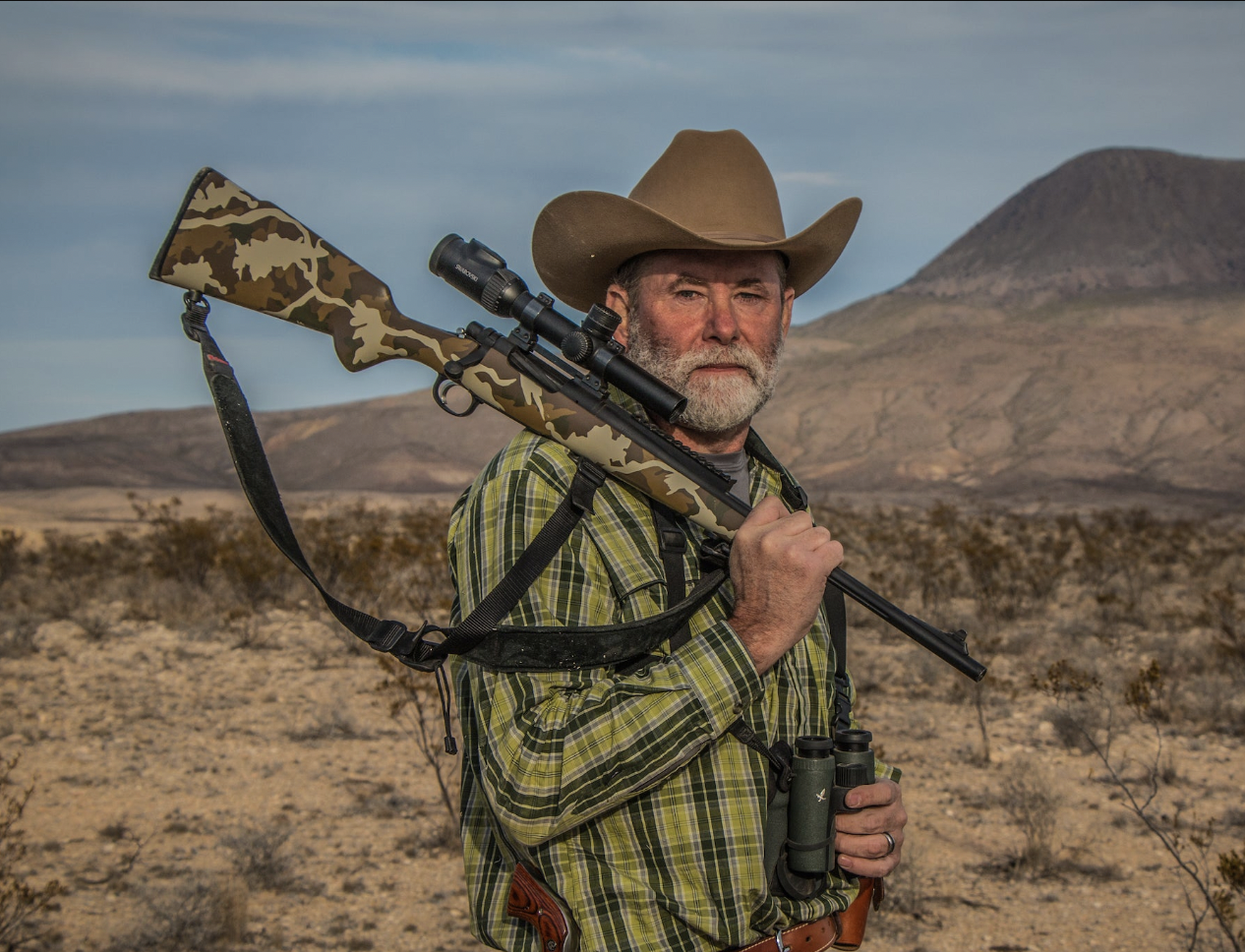 Man holding a great hunting rifle in a desert
