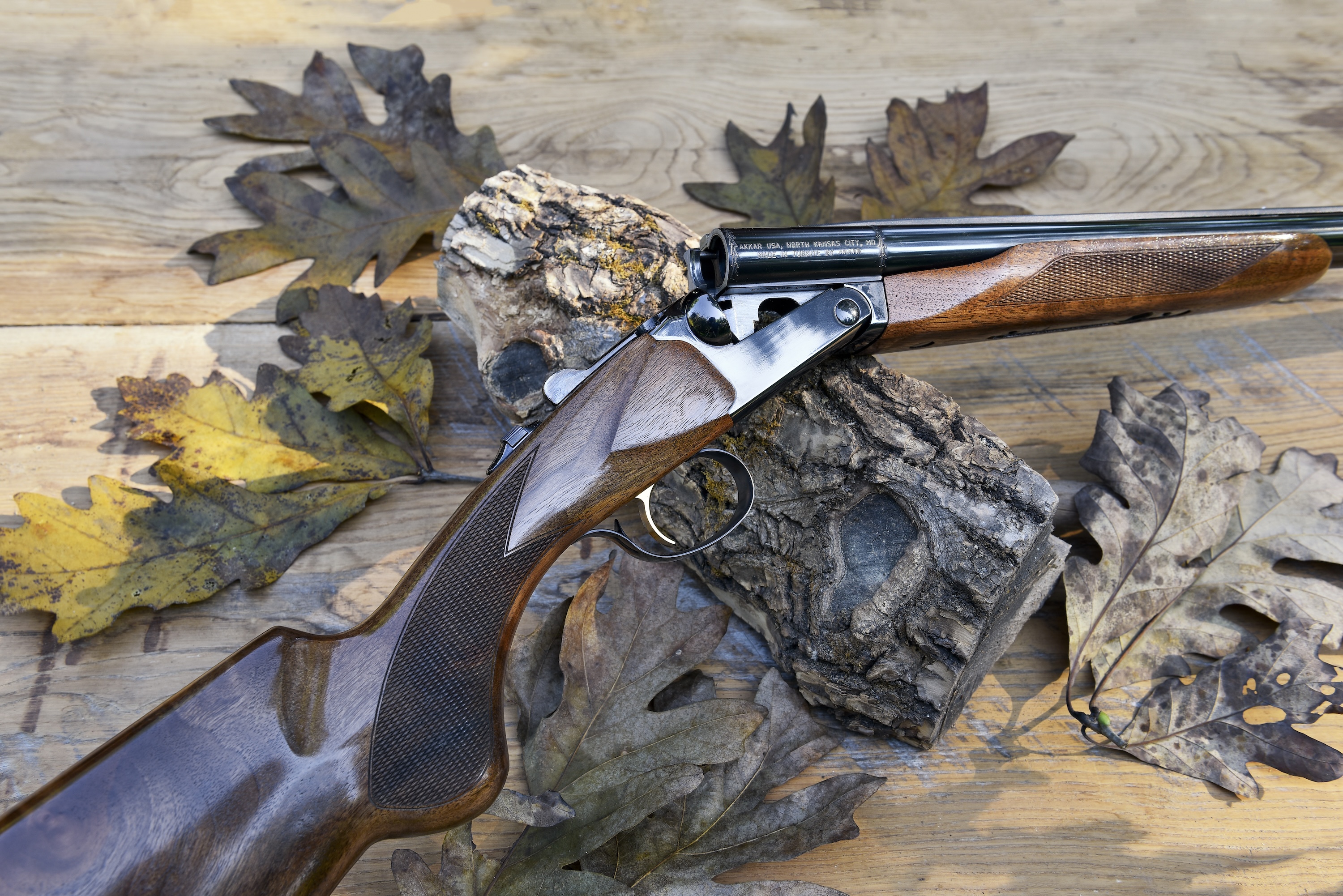 The new Akkar High Noon side-by-side shotgun on barn boards with oak leaves.