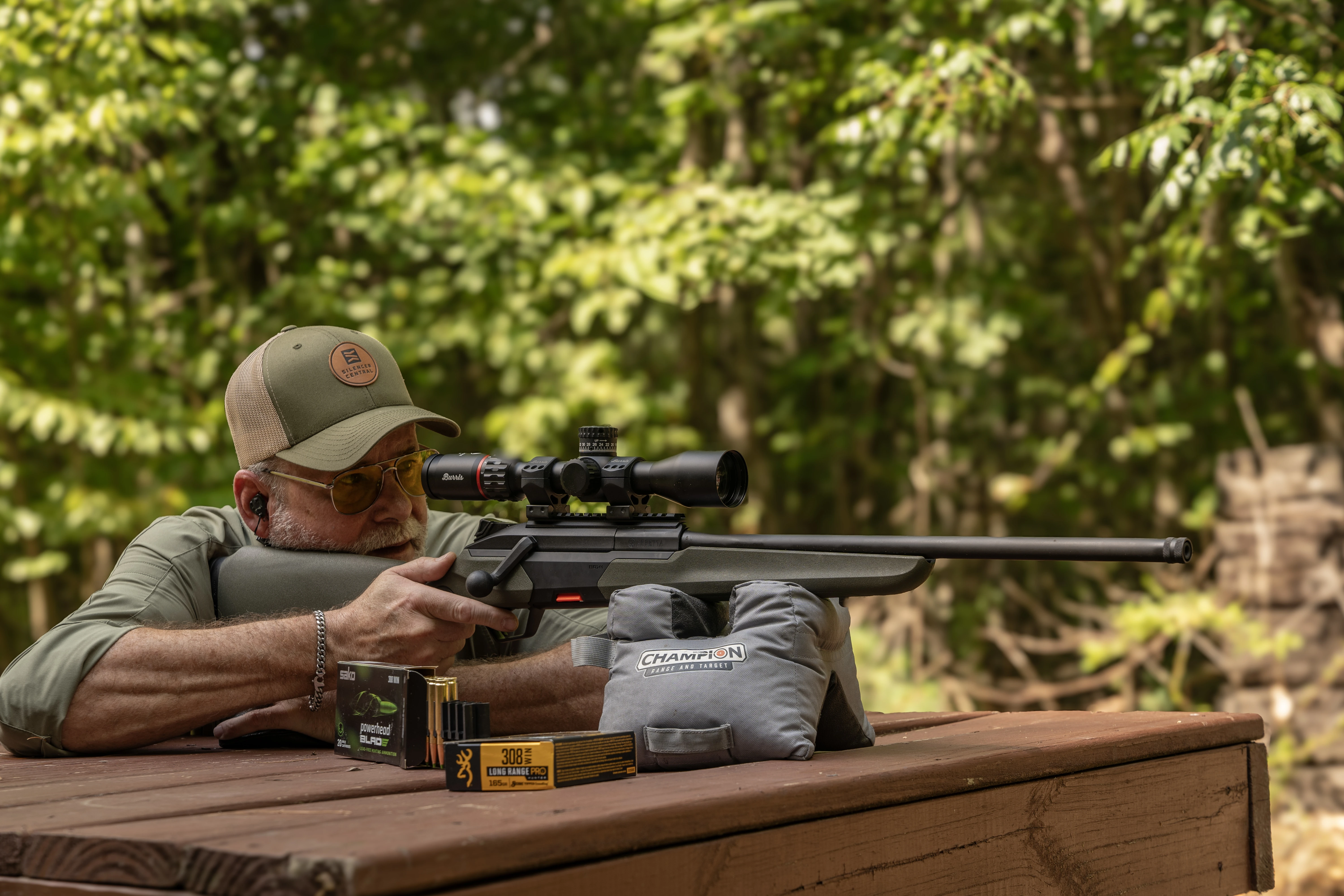 A shooter test fires the Baretta BRX1 rifle from a bench rest with woods in background. 