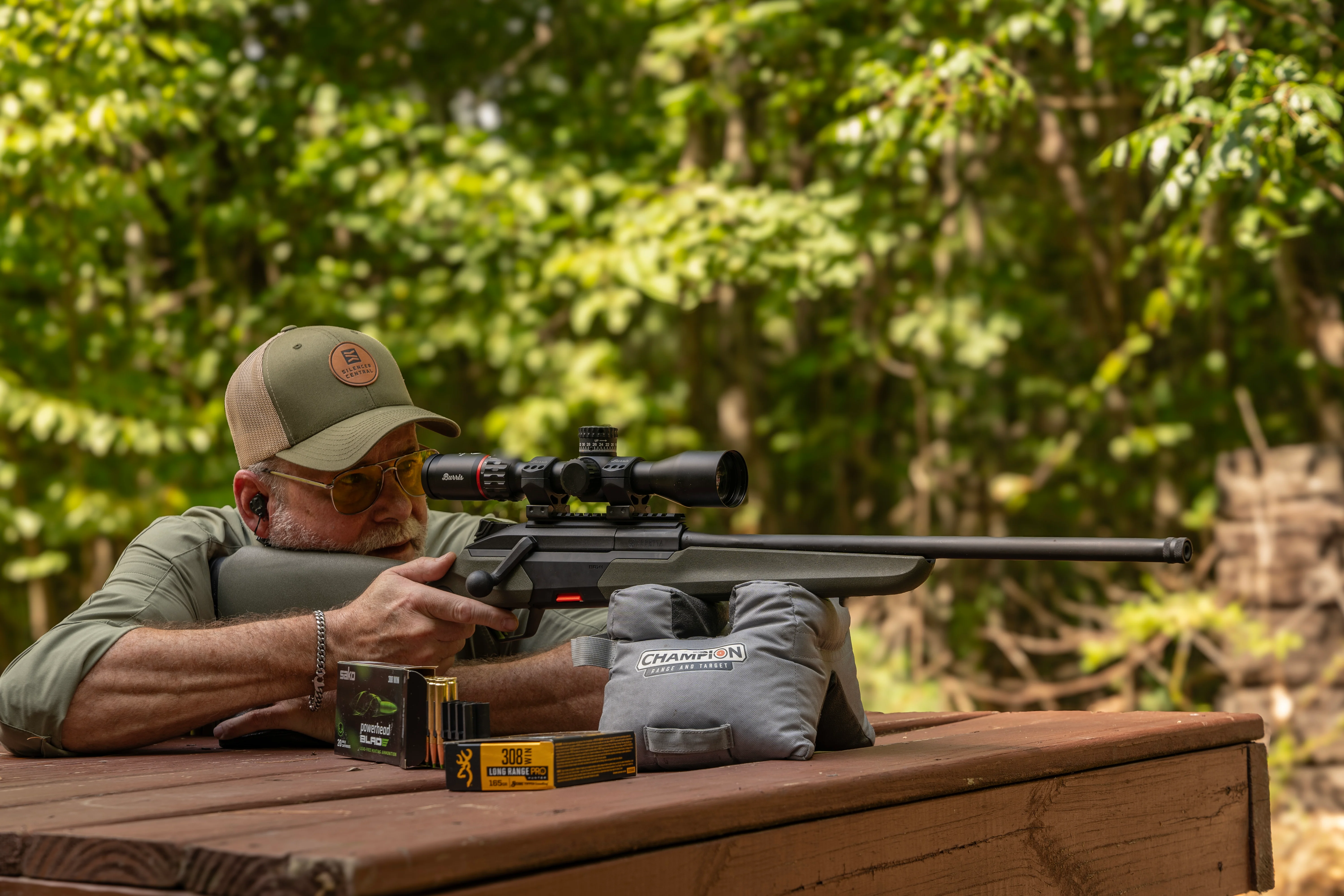 A shooter test fires the Baretta BRX1 rifle from a bench rest with woods in background. 