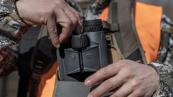 A hunter takes the Leupold BX-4 Range HD binocular from a chest pack.