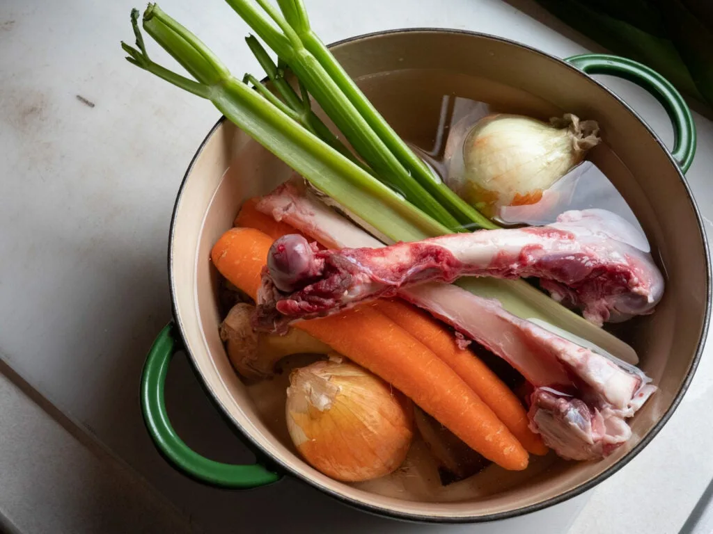 Pot full of bones and vegetables with water.