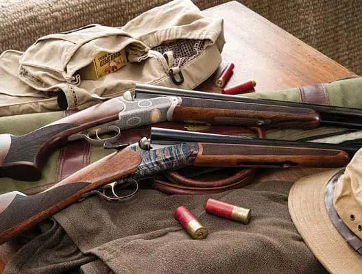 Two shotguns on a hunting jacket and backet.