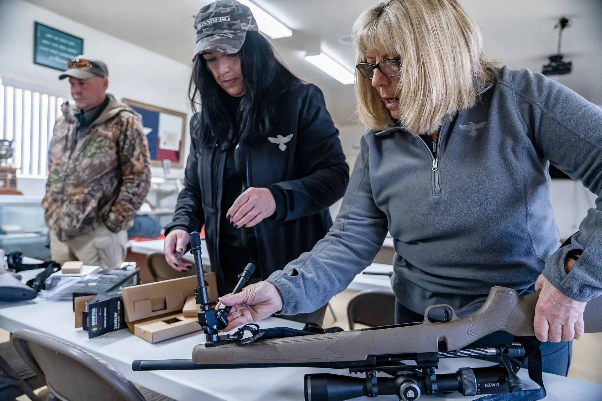 Attendees at a shooting instruction class learn how to set up a bipod on a rifle. 