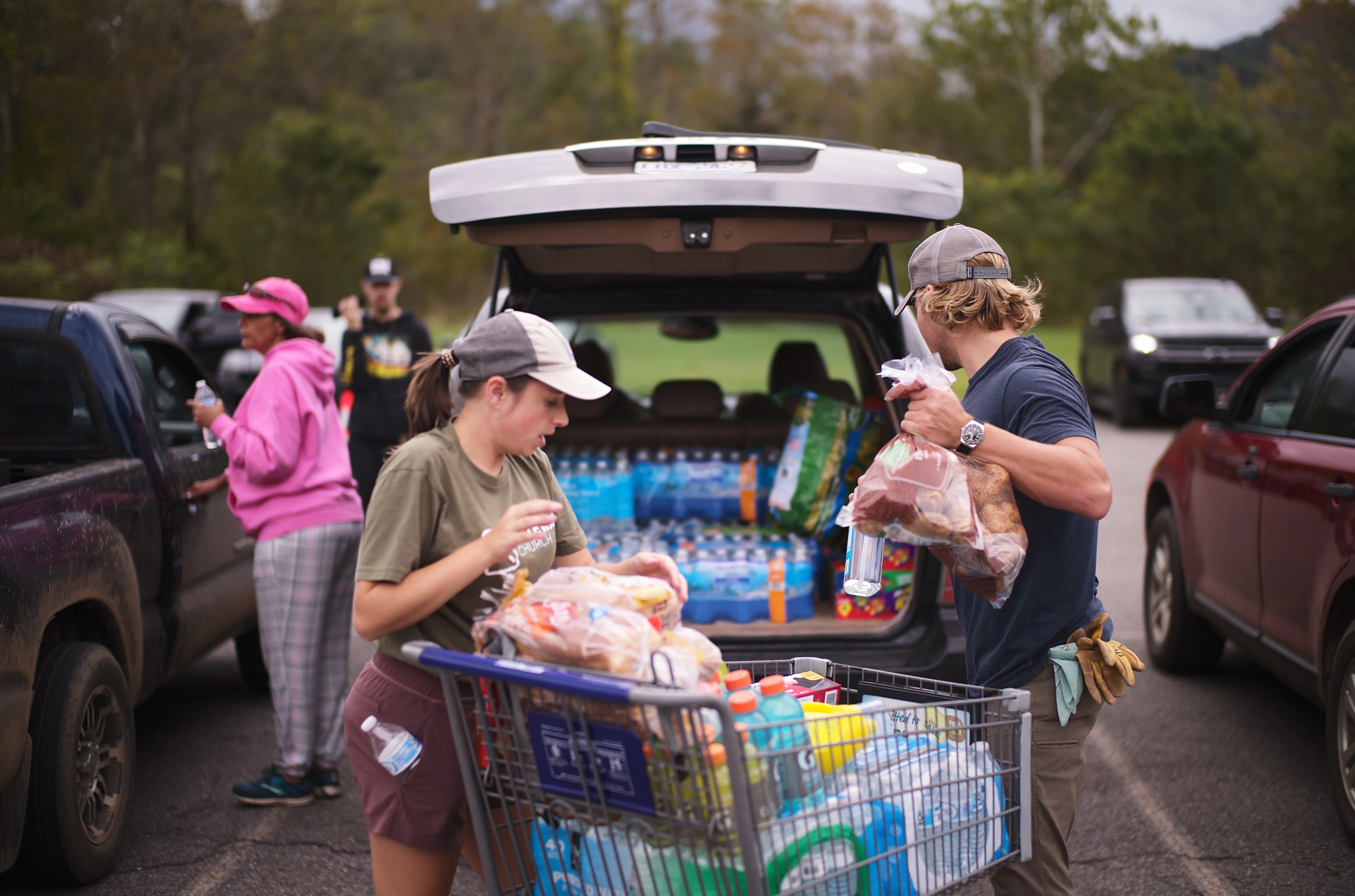 People unloading groceries from the trunk of a car 