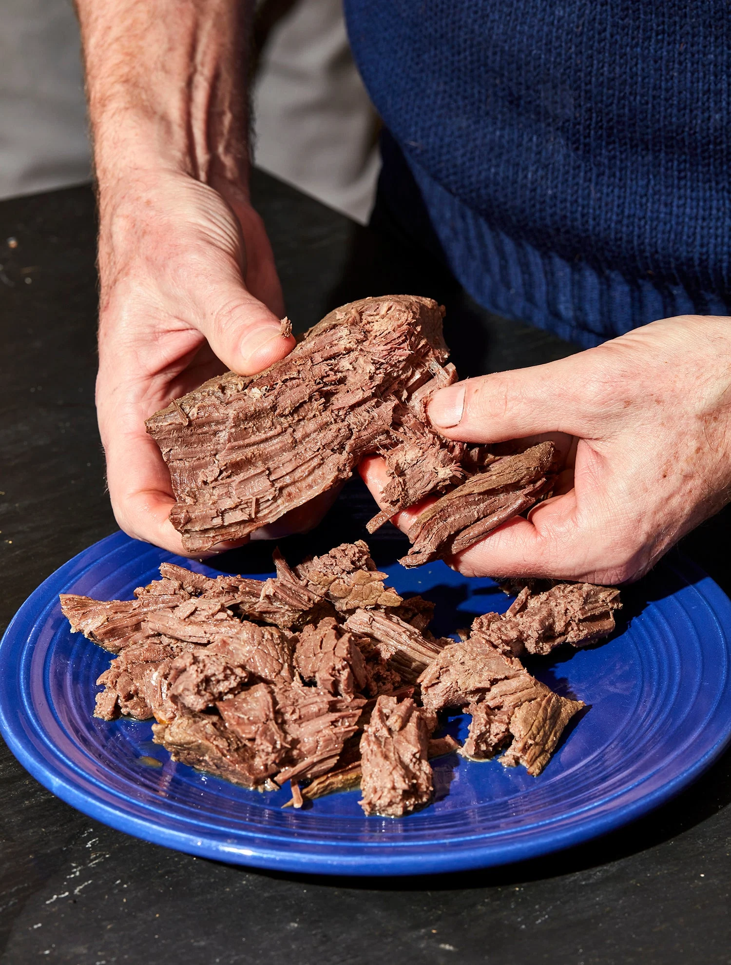 hands pulling meat apart