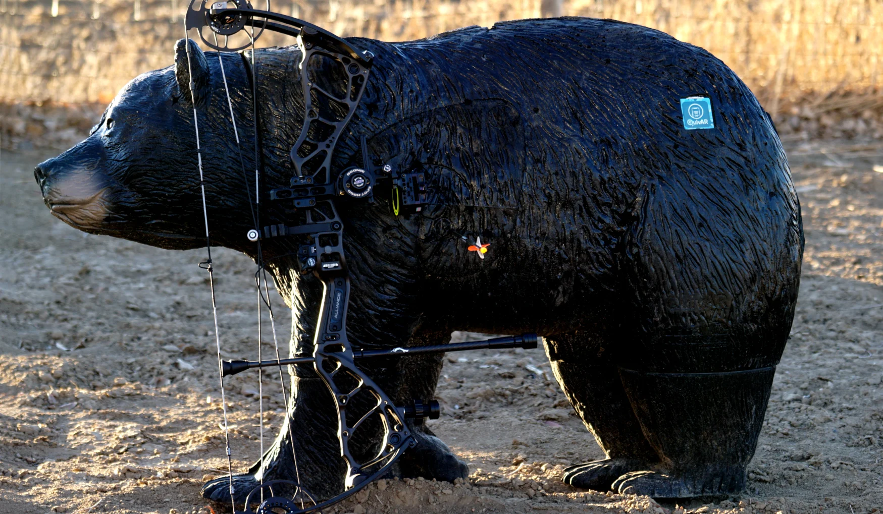 The new Bowtech Alliance compound bow leaning against a 3D bear target with an arrow in the vitals. 