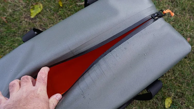 The gray and orange Engel HD30 cooler being held open to show the interior on a grassy lawn. 