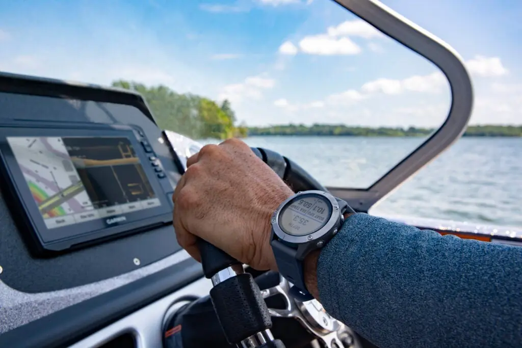 Fisherman driving boat and looking at fish finder