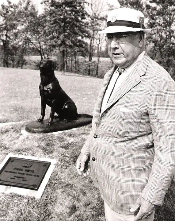 John Olin standing next to a statue of his dog King Buck 