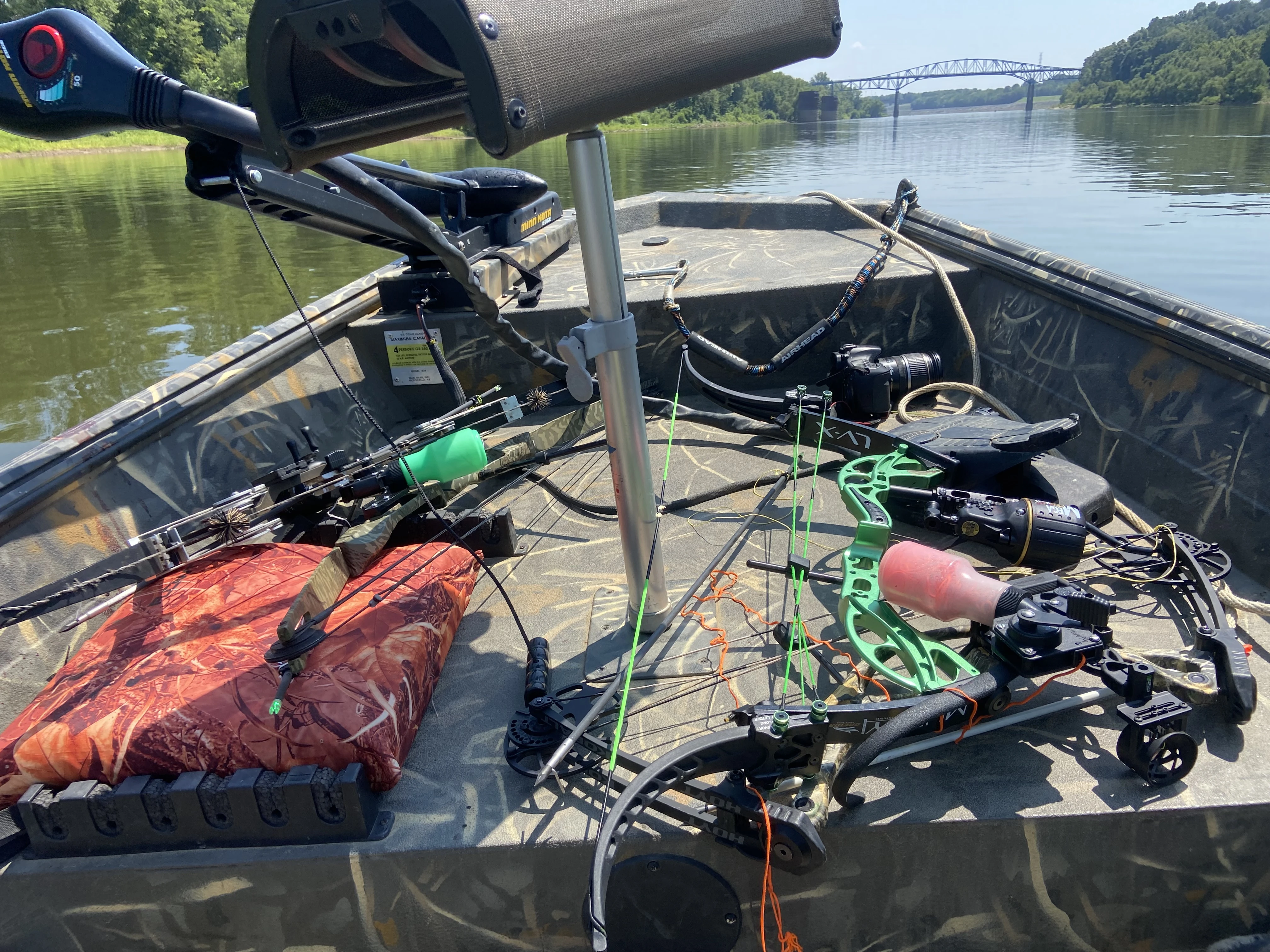 Multiple bows with bowfishing reels sit on the deck of a boat