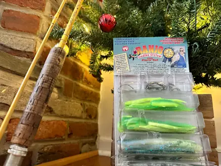 A fishing rod and a pack of banjo minnows under a christmas tree