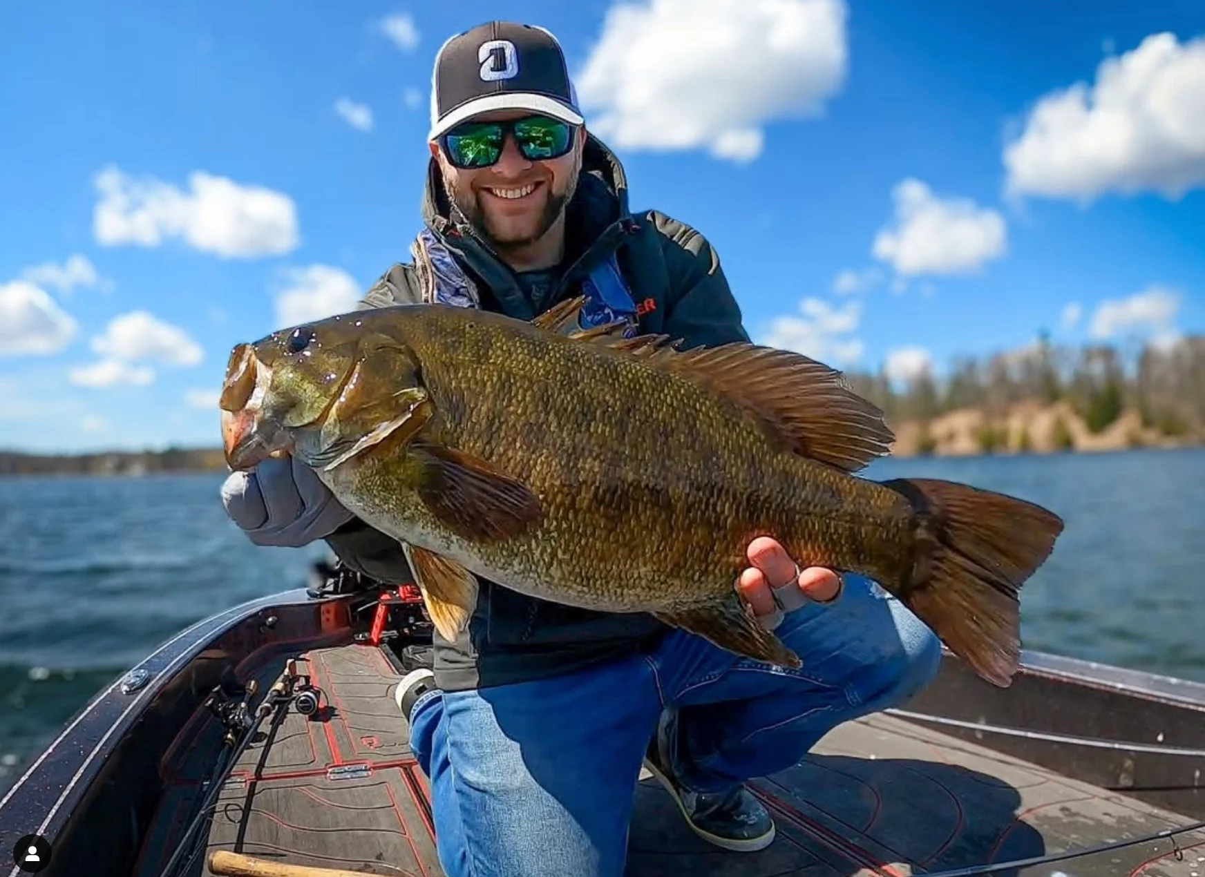 Angler holding up big smallmouth bass on boat