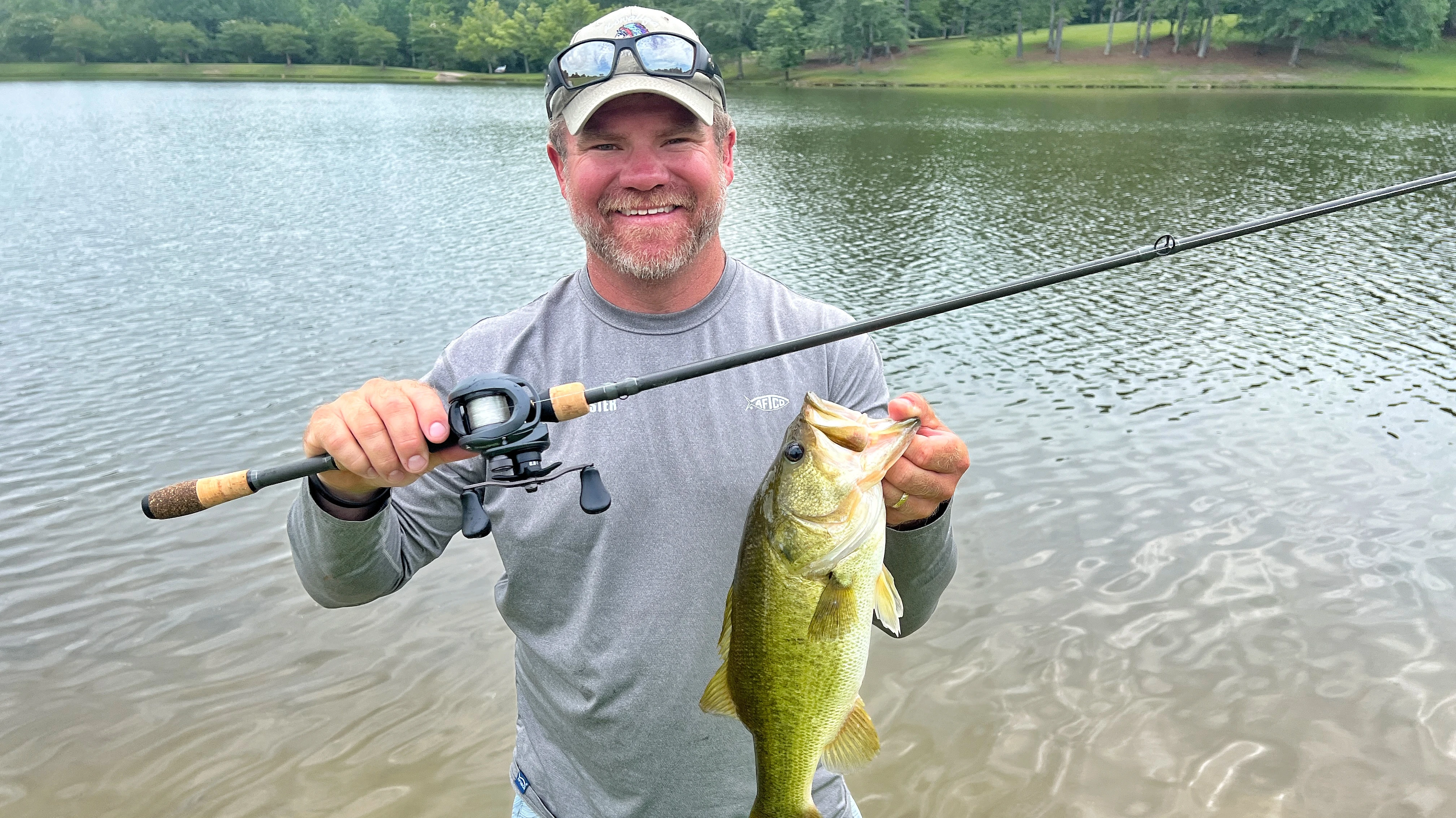 Angler holding up largemouth bass and fishing rod