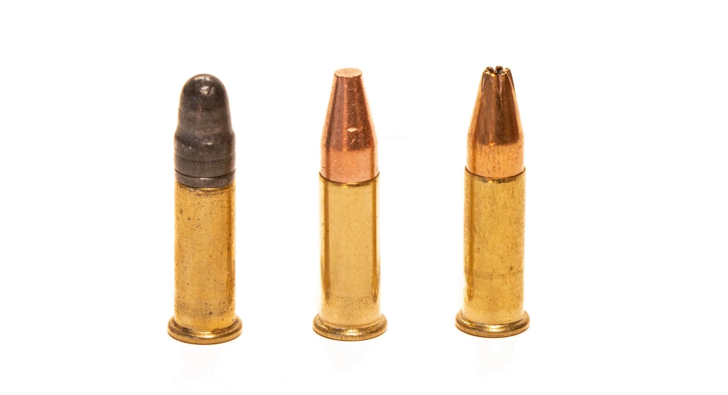 A 22 Long Rifle cartridge on left, next to two 21 Sharp cartridges on the right on a white background