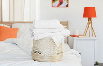 basket full of clean white towels on a bedroom bed