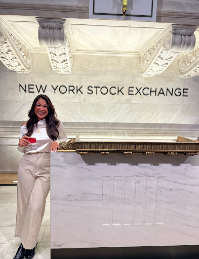 Vrinda Gupta standing at the New York Stock Exchange with a Sequin Visa® Debit Card in her hand.