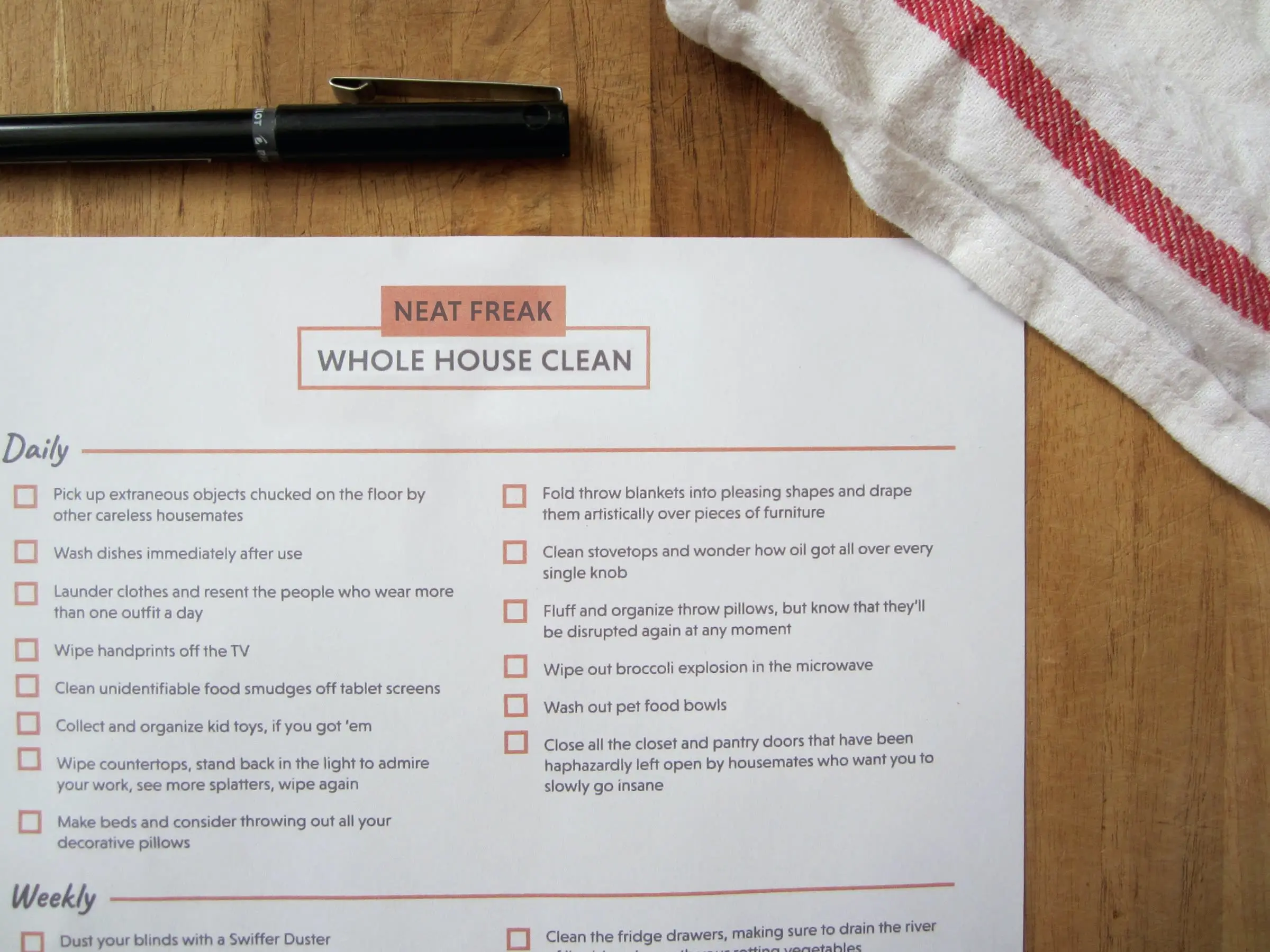 A printed cleaning schedule on a table with a towel and pen