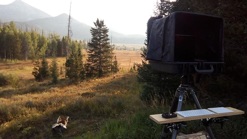 Portable office. Laptop computer on a tripod overlooking mountains