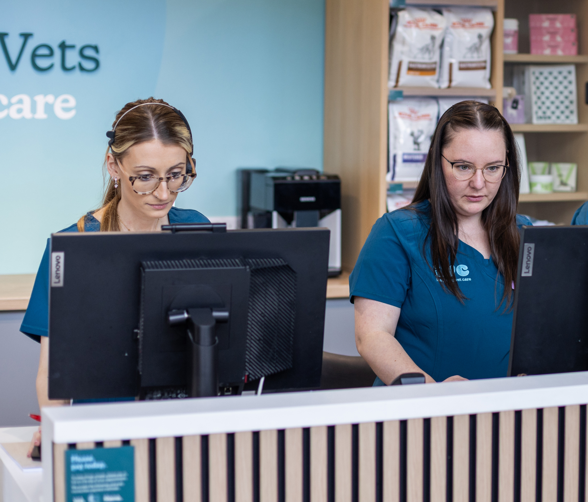 Vet and vet nurse welcoming clients at IVC practice reception desk.