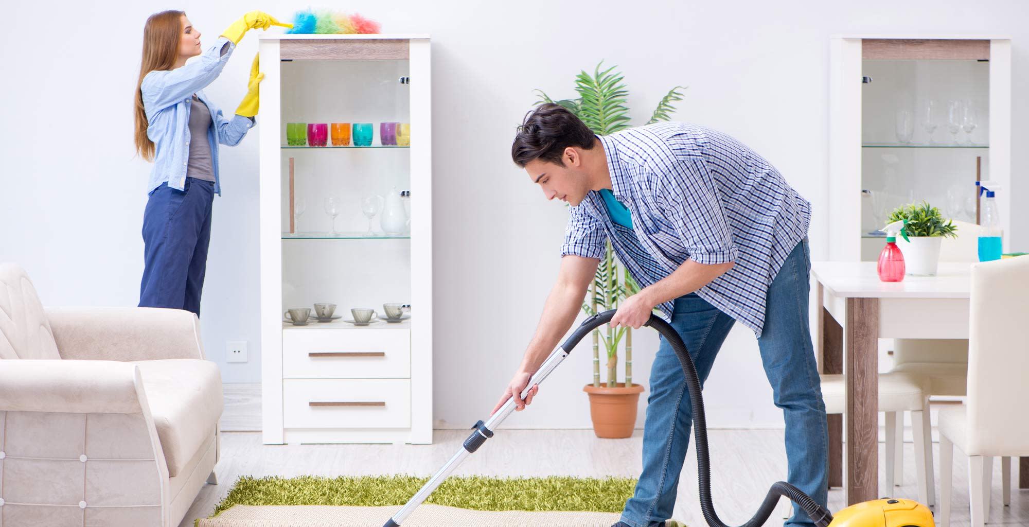 Pareja joven limpiando y ordenando el living de la casa
